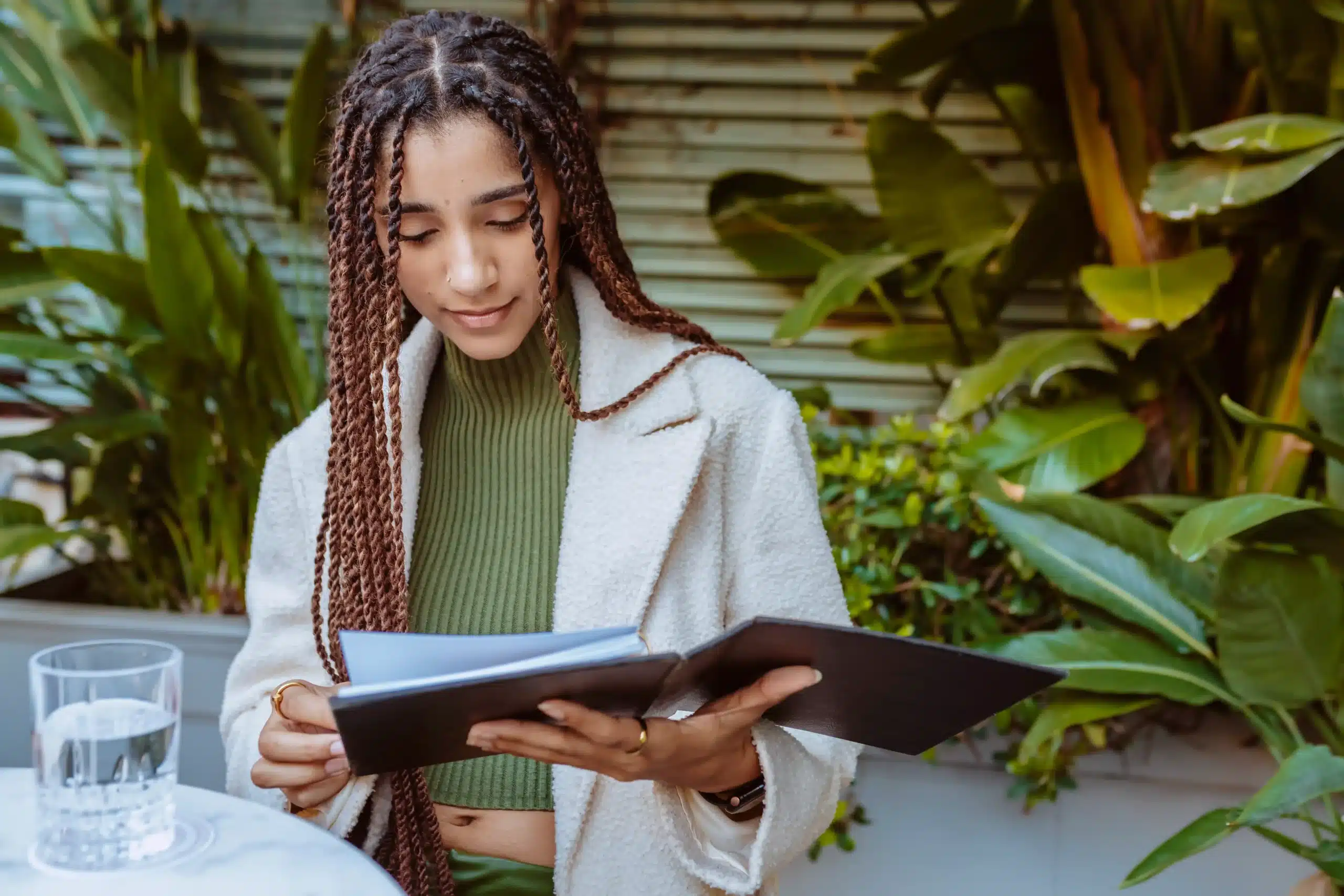 A imagem mostra uma jovem mulher, com tranças no cabelo, lendo um documento. Ilustra o texto sobre Documento Provisório de Registro Nacional Migratório.