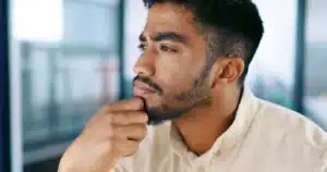 A imagem mostra um jovem negro, pensativo, olhando para o horizonte com uma das mãos no queixo. Ilustra o texto venezuelanos no Brasil.