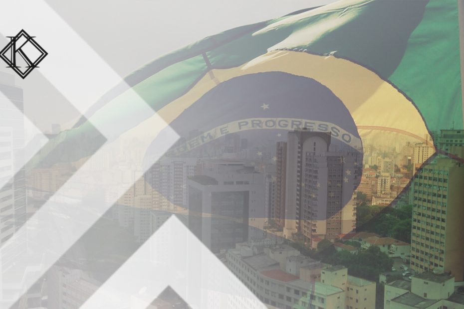 A imagem mostra uma bandeira do Brasil sobreposta a uma imagem de uma cidade brasileira, e ilustra a publicação "Embaixadas e Consulados no Brasil: lista de endereços e contatos", da Koetz Advocacia.