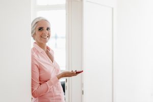 A imagem mostra uma mulher segurando um celular, sorrindo para a câmera e ilustra o texto: Residence permit for foreign investor in Brazil da Koetz Advocacia.