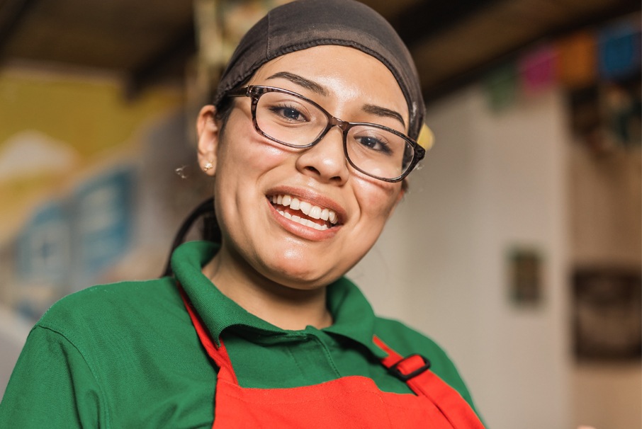 A imagem mostra uma mulher sorrindo, vestindo um avental. Imagem do texto Visa de trabajo de Brasil: "¿cuáles son las opciones y cómo aplicar?" de Koetz Advocacia