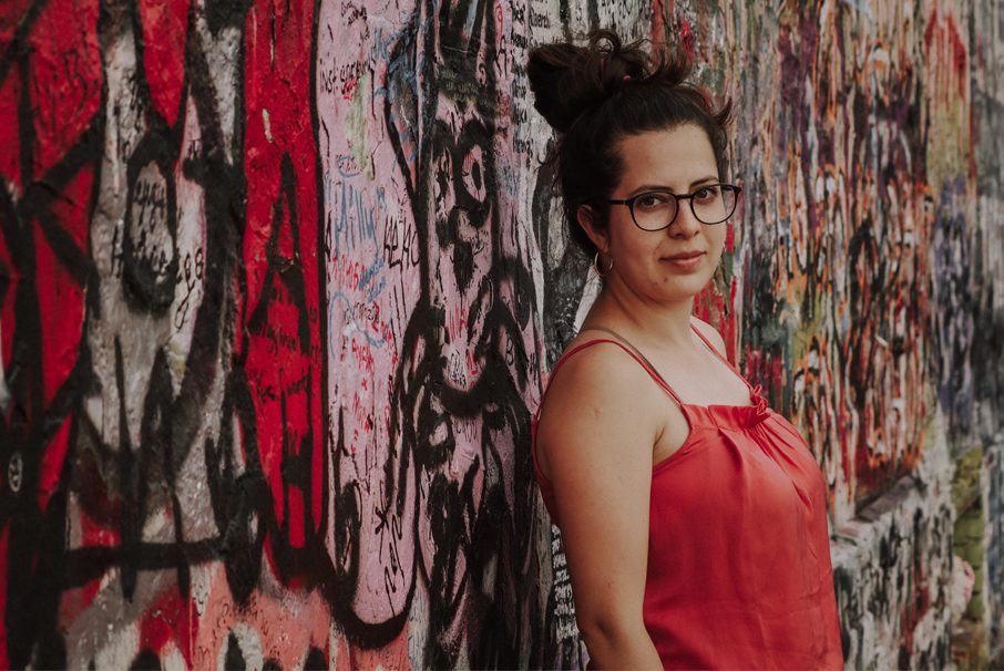 garota jovem encostada em uma parede com desenhos colorida olhando para a câmera, imagem do texto "Visto brasileiro para atividades artísticas ou esportivas" de Koetz Advocacia