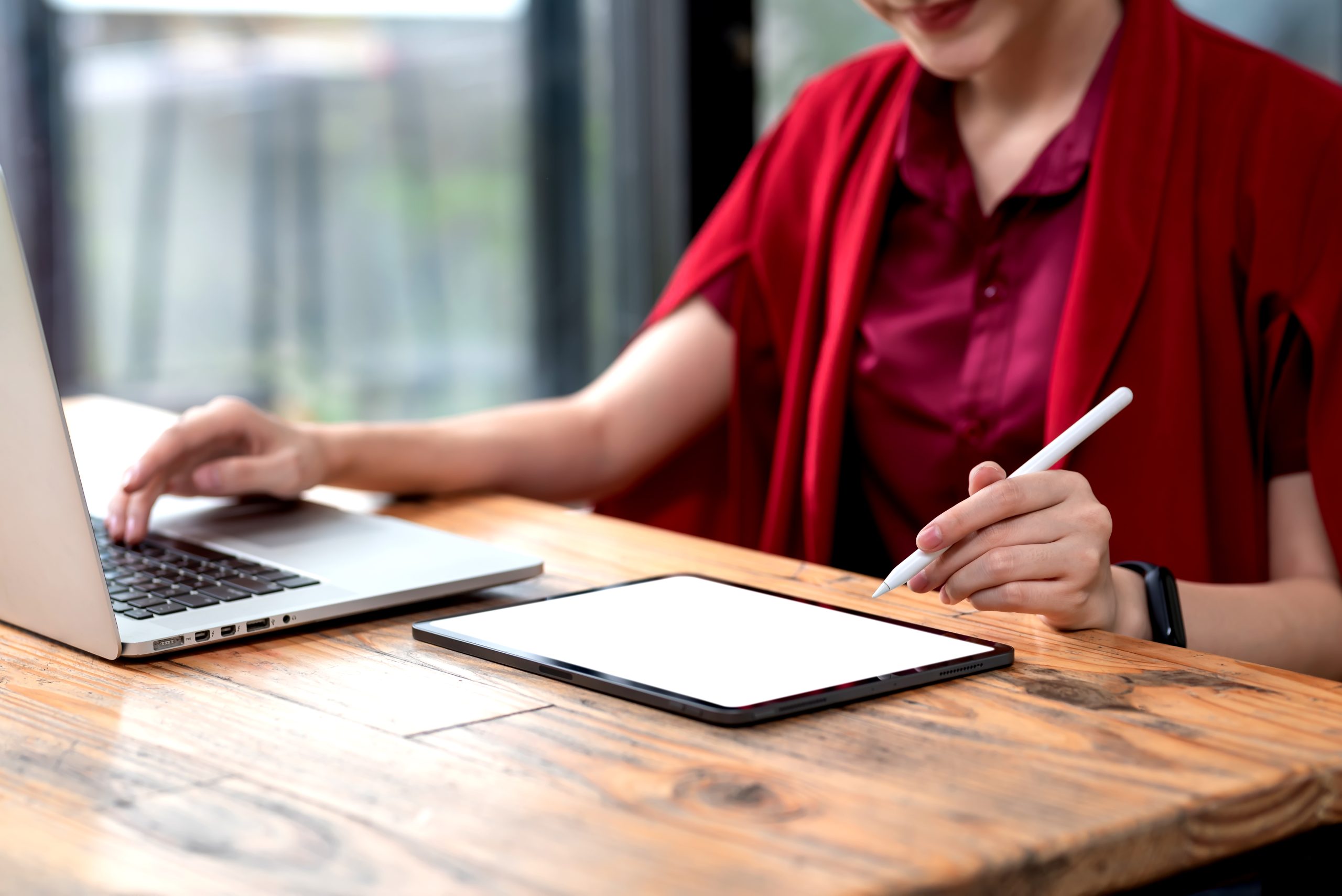 A imagem mostra uma mulher usando o notebook e o tablet, sentada em uma cadeira e ilustra o texto: Tax Resident and Non-Resident da Koetz Advocacia.