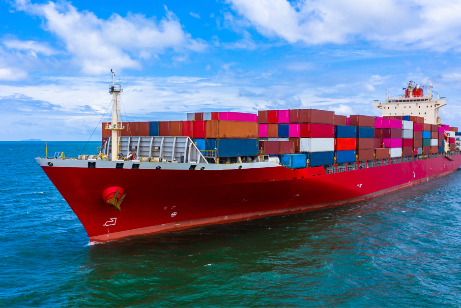 A imagem mostra um navio em alto mar cheio de containers.