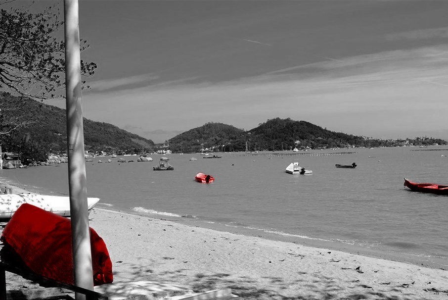 A imagem mostra a praia de Florianópolis, com vários barcos no mar. A imagem ilustra o texto 