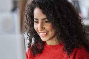 A imagem mostra uma mulher sorrindo enquanto olha para a tela do computador. Imagem do texto 