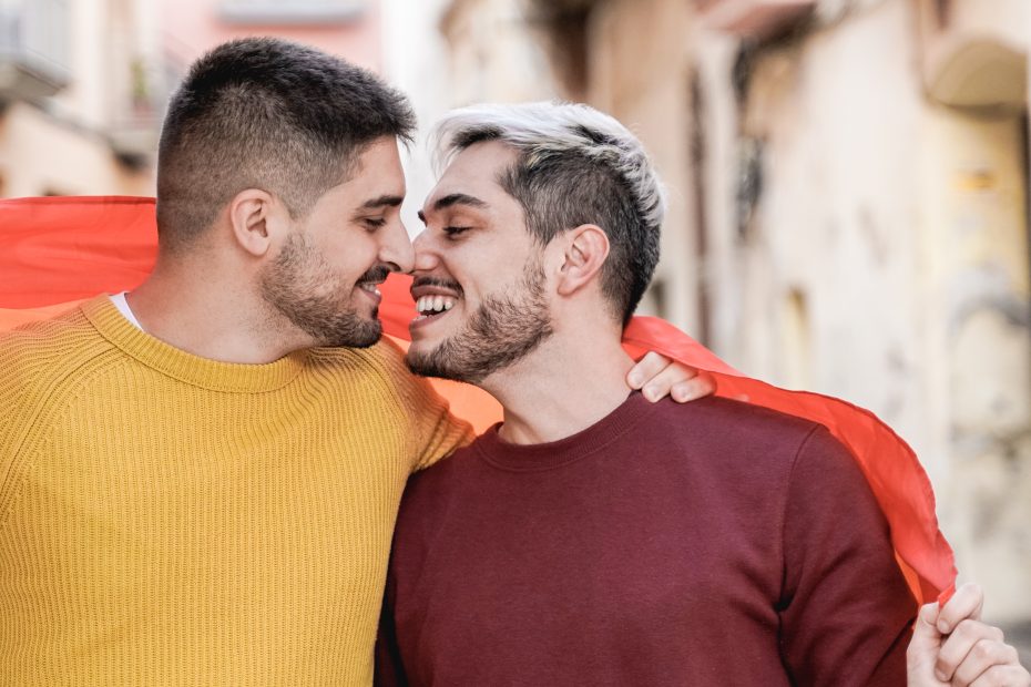 A foto mostra dois homens entrelaçados em uma bandeira e ilustra o texto: Gay marriage in Brazil da Koetz Advocacia.