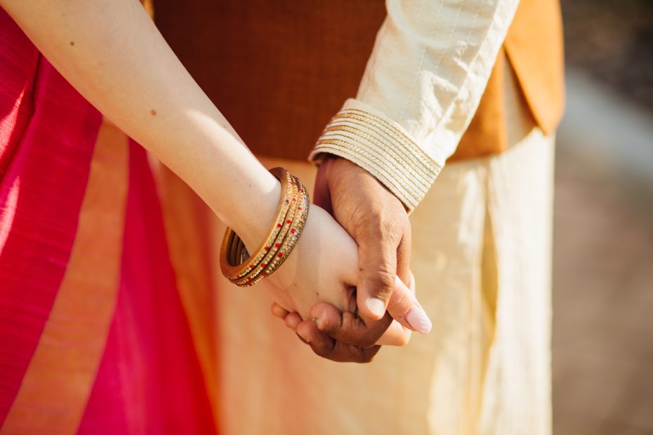 A imagem mostra em foco um casal interracial de mãos dadas e ilustra o texto: Polygamy: foreigners and the right to marry several wives da Koetz Advocacia.