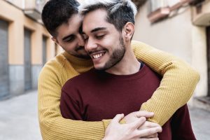 A foto mostra dois homens entrelaçados em um abraço e ilustra o texto: Casamento gay no Brasil da Koetz Advocacia.