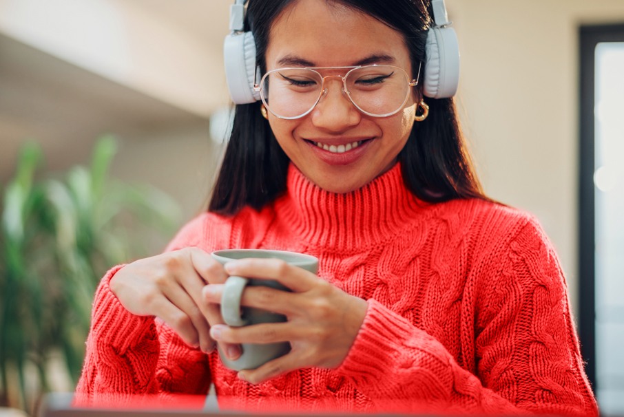 La imagen muestra a una mujer asiática usando su computadora y bebiendo té. ilustrando el articulo "Requisitos para la Visa Brasileña"