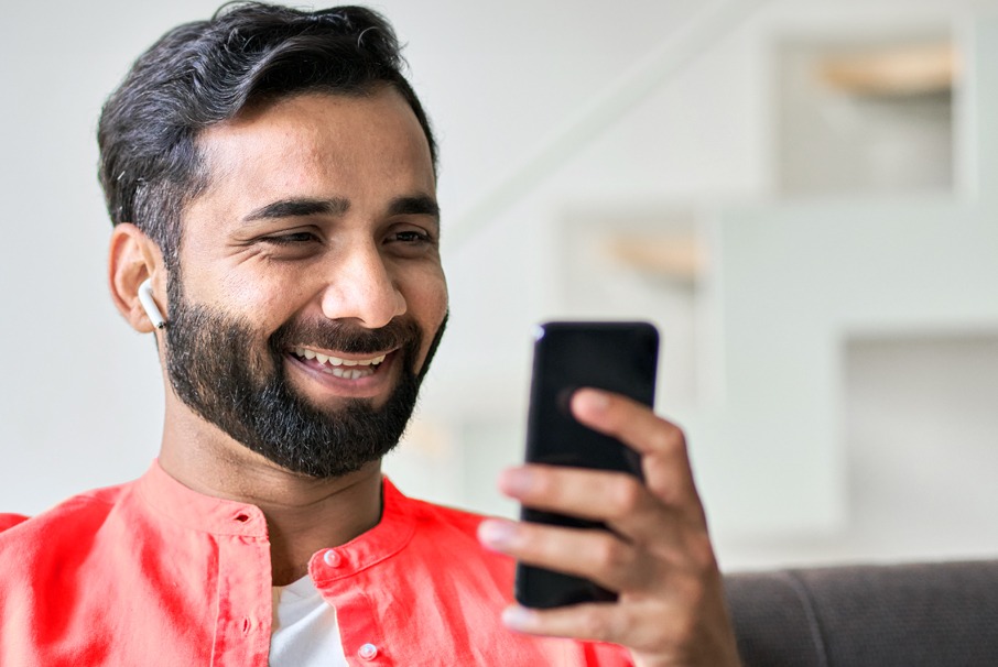 La imagen muestra a un hombre sonriente usando su teléfono celular, ilustrando el articulo 