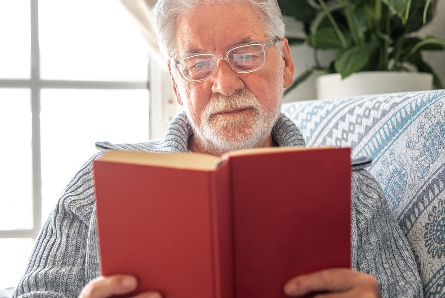A imagem mostra um homem maduro, lendo um livro. A imagem ilustra o texto 