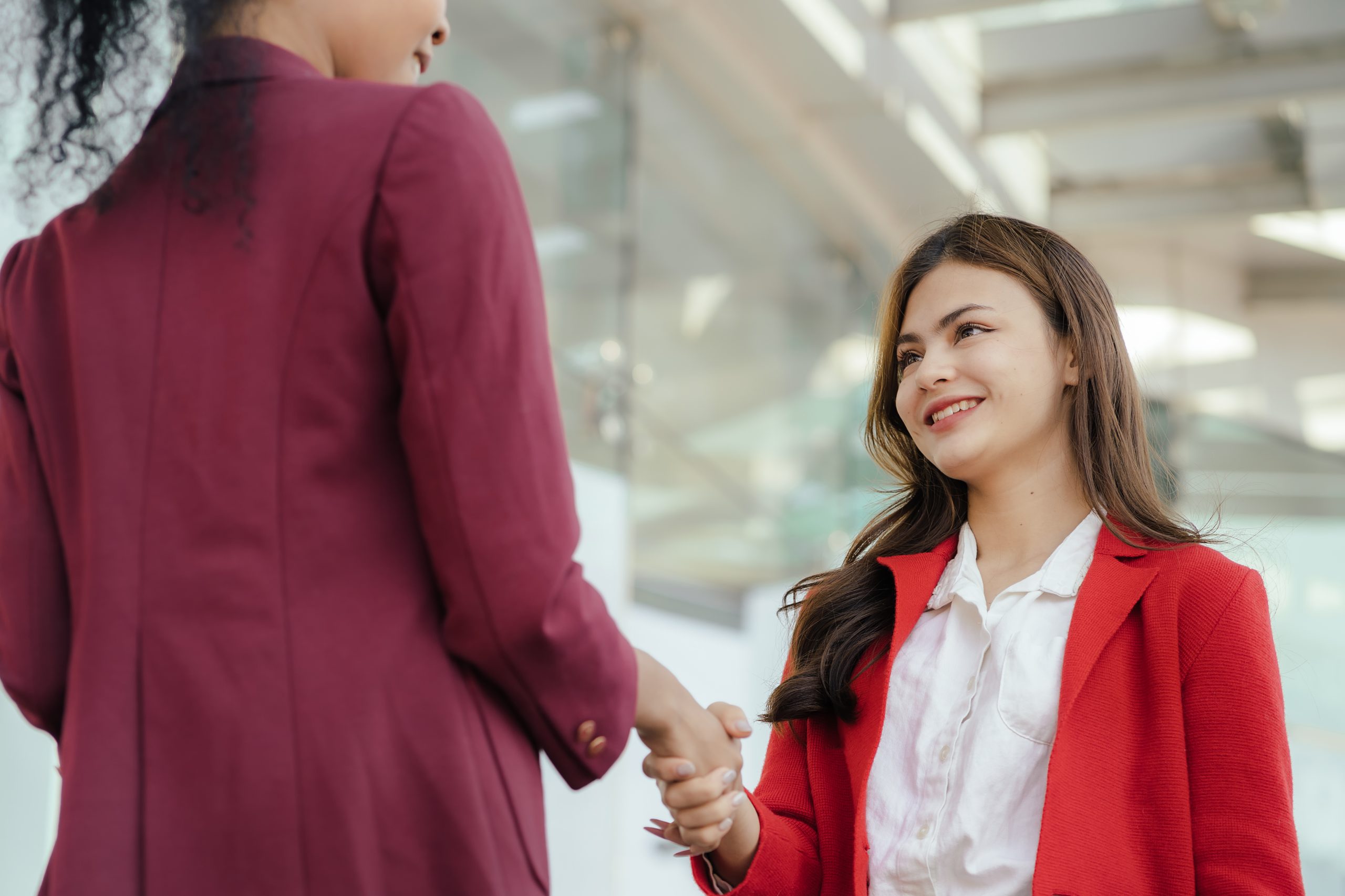 A imagem mostra duas mulheres em um ambiente formal, de negócios, apertando as mãos e ilustra o texto: Export mediation contract da Koetz Advocacia.