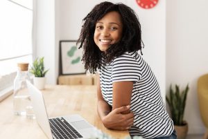 The image shows a girl smiling at the camera, with her notebook and cell phone on the table. ilustrating the article 