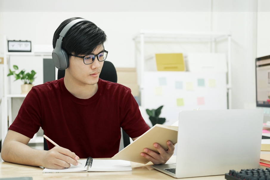 The image shows a young man studying in front of the computer. ilustrating the article "Certificate of Proficiency in Portuguese for Foreigners" Koetz Advocacia