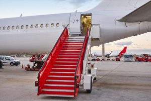 A imagem mostra um aeroporto com avião e escadas. A imagem ilustra o texto 