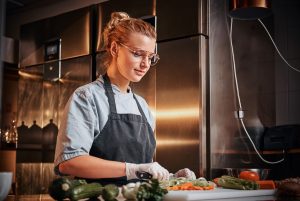 The image shows a female chef cooking in a restaurant. ilustrating the article 