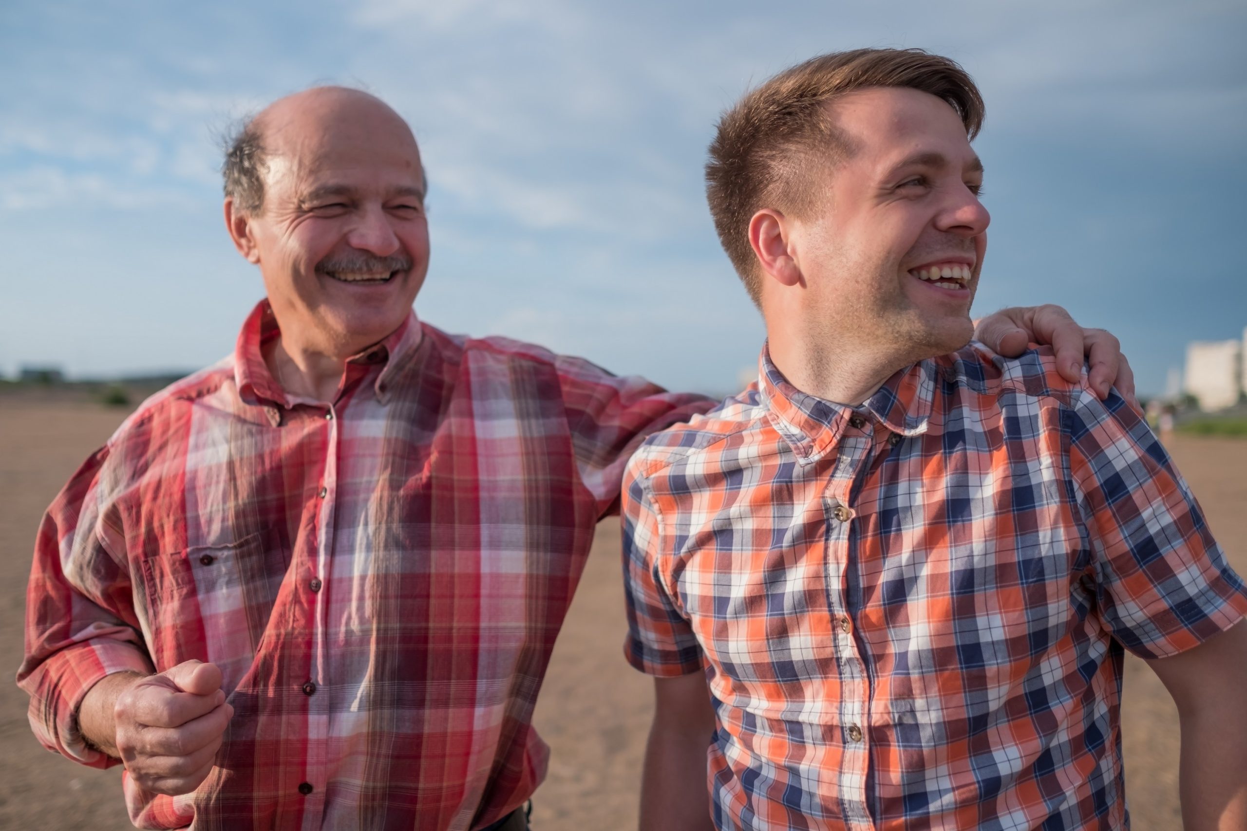 A imagem mostra um pai de meia-idade, abraçado com seu filho adulto, enquanto os dois sorriem e caminham em área livre e ilustra o texto: Herdeiro: quem é, quais os direitos e cuidados que precisa ter da Koetz Advocacia.