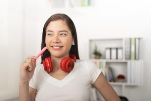 La imagen muestra a una mujer joven sonriendo, con auriculares. ilustrando el articulo 