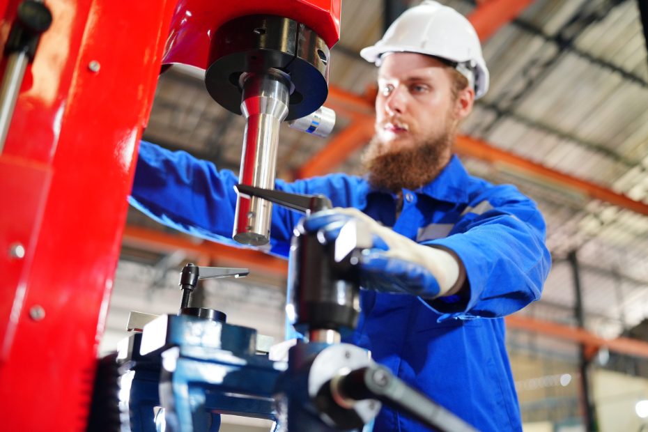 A imagem mostra um engenheiro industrial trabalhando em uma fábrica, manuseando uma máquina e ilustra o texto: Importação de máquinas industriais: o que você precisa saber da Koetz Advocacia.