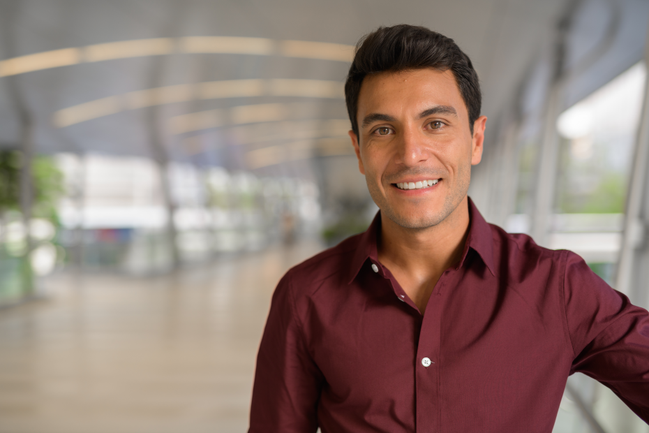 A imagem mostra um jovem homem, com camisa social, sorrindo para a câmera e ilustra o texto: Work permit for foreigners with a permanent visa da Koetz Advocacia.
