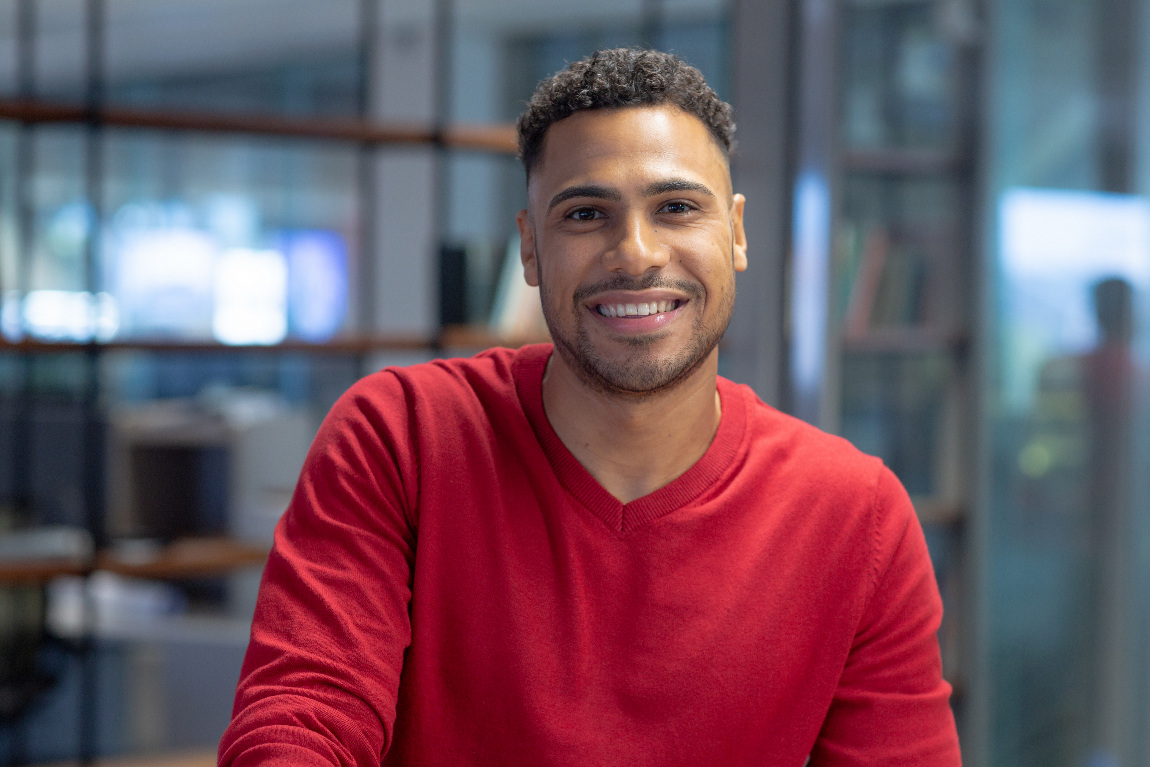 A imagem mostra um jovem homem hispânico, sorrindo para a câmera e ilustra o texto: Como o estrangeiro pode trabalhar no Brasil? da Koetz Advocacia.