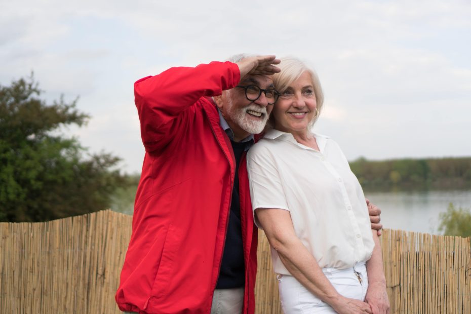 A imagem mostra um casal na melhor idade sorrindo e olhando para o horizonte, e ilustra a publicação "Planejamento Sucessório: o que é como ele protege o seu futuro e da sua família", da Koetz Advocacia.