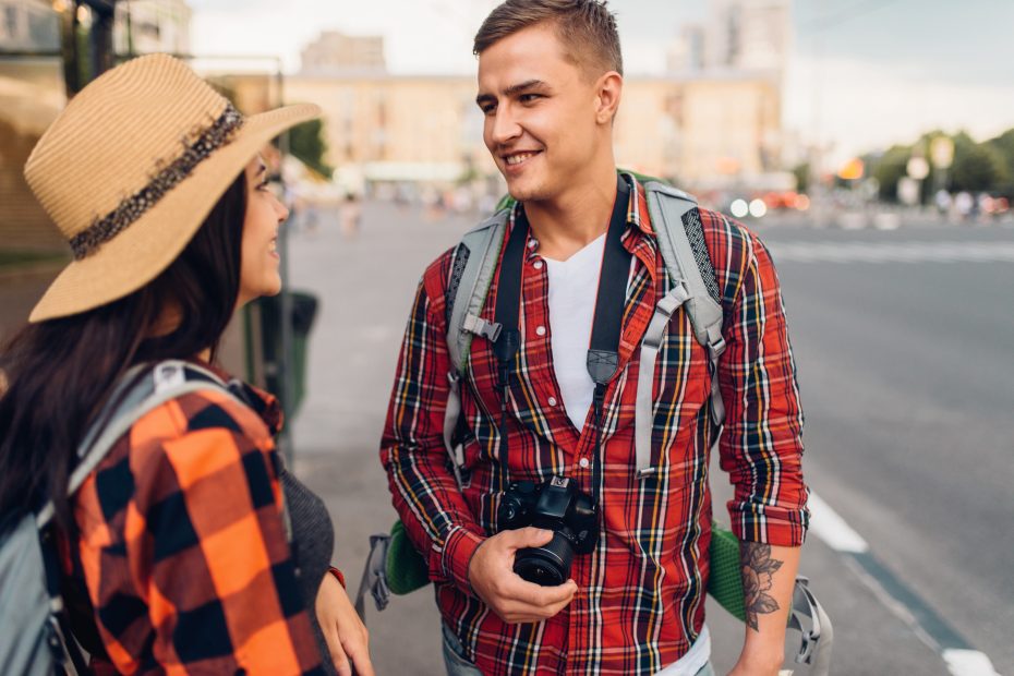 A imagem mostra um casal jovem de turistas, com mochilas, andando pelas ruas e ilustra o texto: Visto de turista para o Brasil para cidadãos americanos, canadenses, australianos e japoneses da Koetz Advocacia.