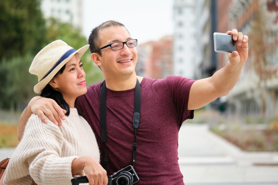 A imagem mostra um casal feliz, no ar livrem tirando uma selfie enquanto sorri e ilustra o texto: Tourist Visa for Brazil for US, Canadian, and Australian Citizens da Koetz Advocacia.