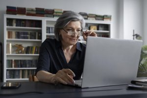 A imagem mostra uma mulher na melhor idade fazendo uma pesquisa no computador, e ilustra a publicação 