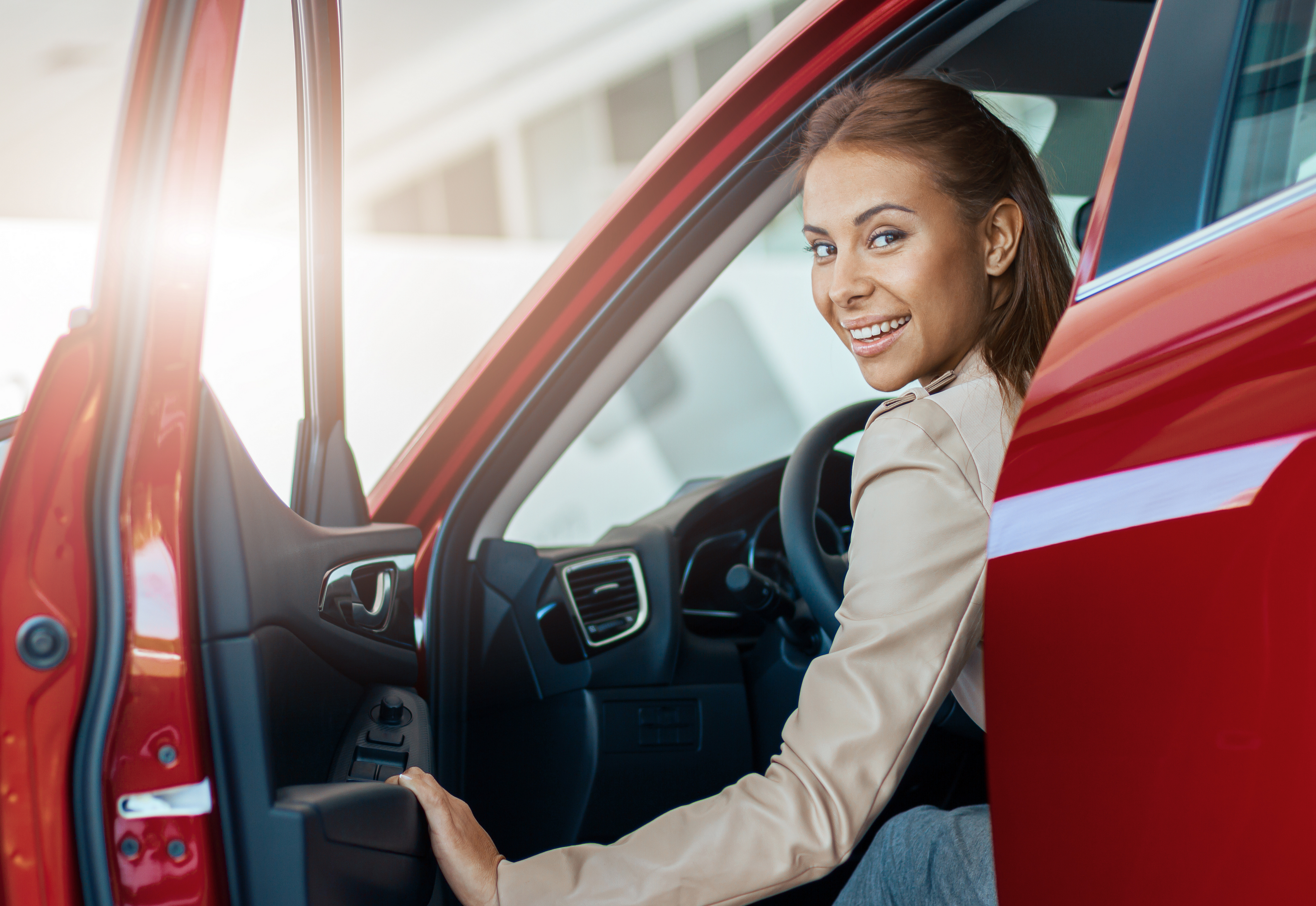 A imagem mostra uma jovem mulher sorrindo, dentro de seu carro, no banco do motorista e ilustra o texto: Import and export of own vehicles da Koetz Advocacia.