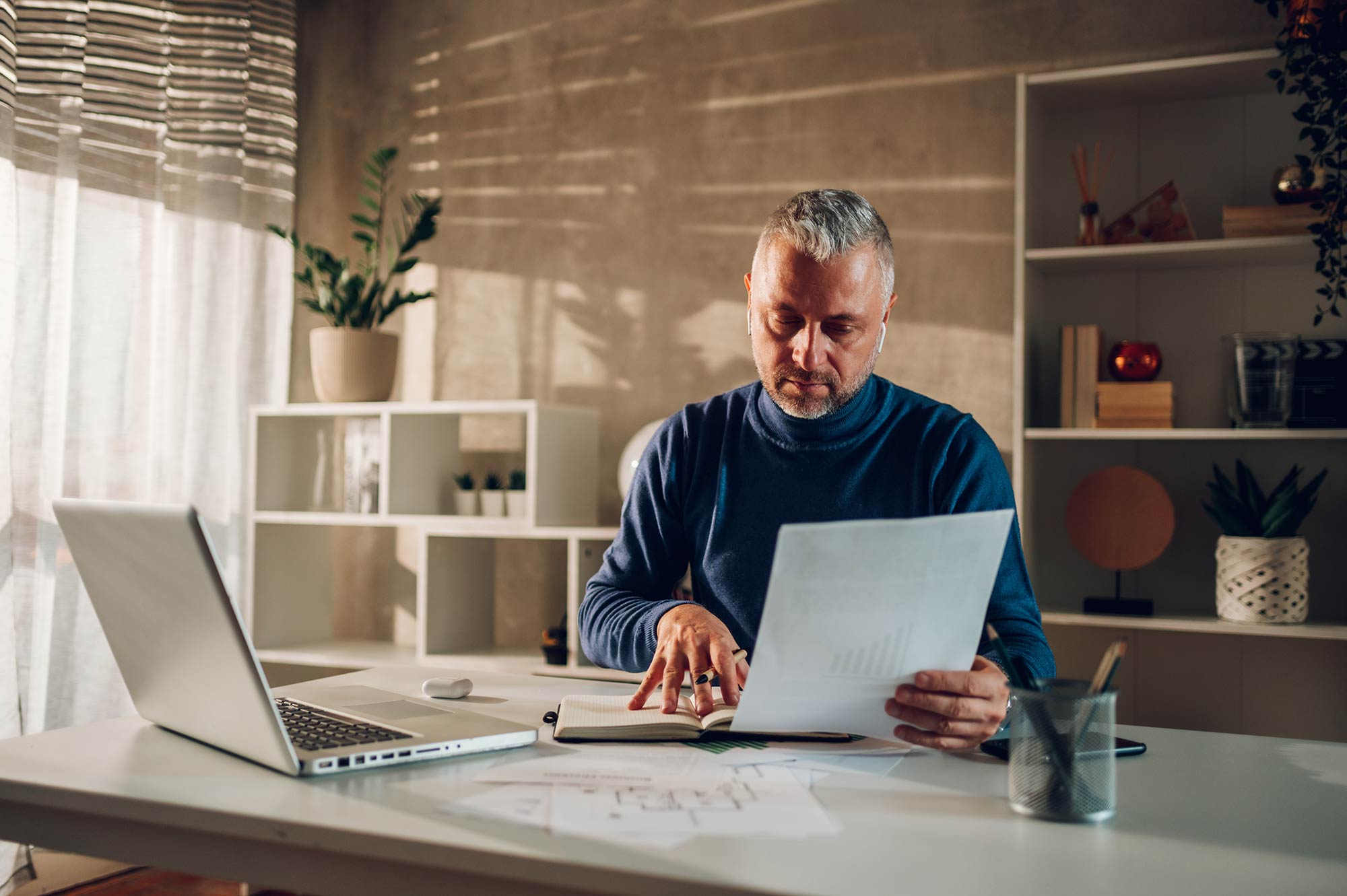 A imagem mostra um homem da terceira idade lendo documentos em seu escritório, e ilustra a publicação da Koetz Advocacia: ITCMD O que é o imposto, declaração, isenção e mais!