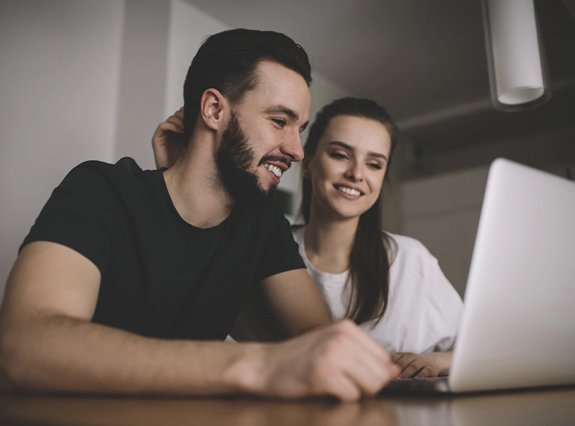 The image shows a young couple researching something on their computer. The image illustrates the text 