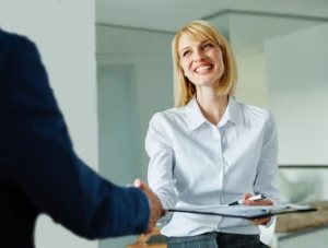 La imagen muestra a una joven empresaria estrechando la mano de un compañero de trabajo en una reunión de acuerdo de inversión en oficina.