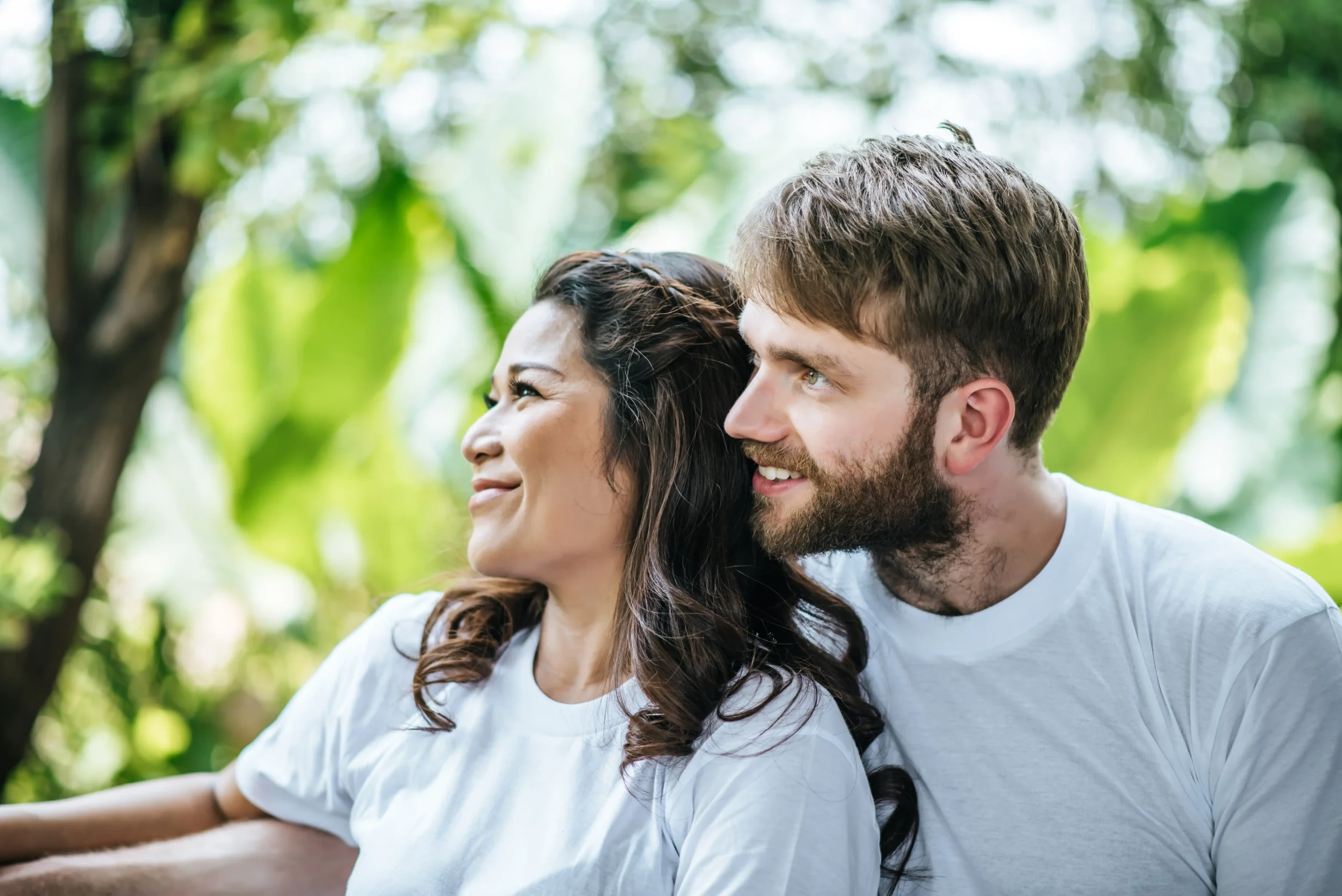La imagen muestra a una pareja sonriente abrazándose al aire libre. Ilustra el texto sobre casarse con un extranjero en Brasil.