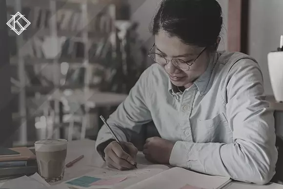 Woman sitting at a table taking notes. The image illustrates the publication "National Migration Registration Card: what is it and how to obtain it?"