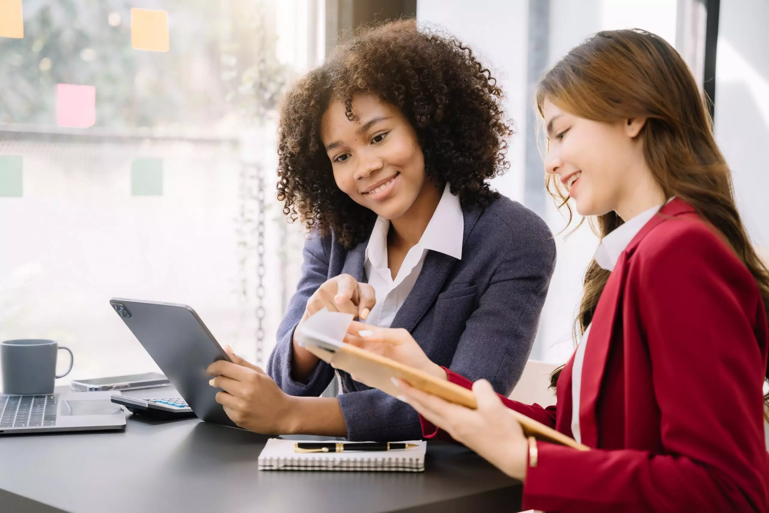 La imagen muestra dos mujeres vestidas formalmente, en un ambiente corporativo, conversando y sonriendo e ilustra el texto: Cómo obtener una visa brasileña invirtiendo en innovación de Koetz Advocacia.