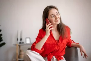 La imagen muestra a una joven usando un teléfono celular mientras está sentada en un sillón e ilustra el texto: Visa brasileña vencida: cómo regularizarla de Koetz Advocacia.