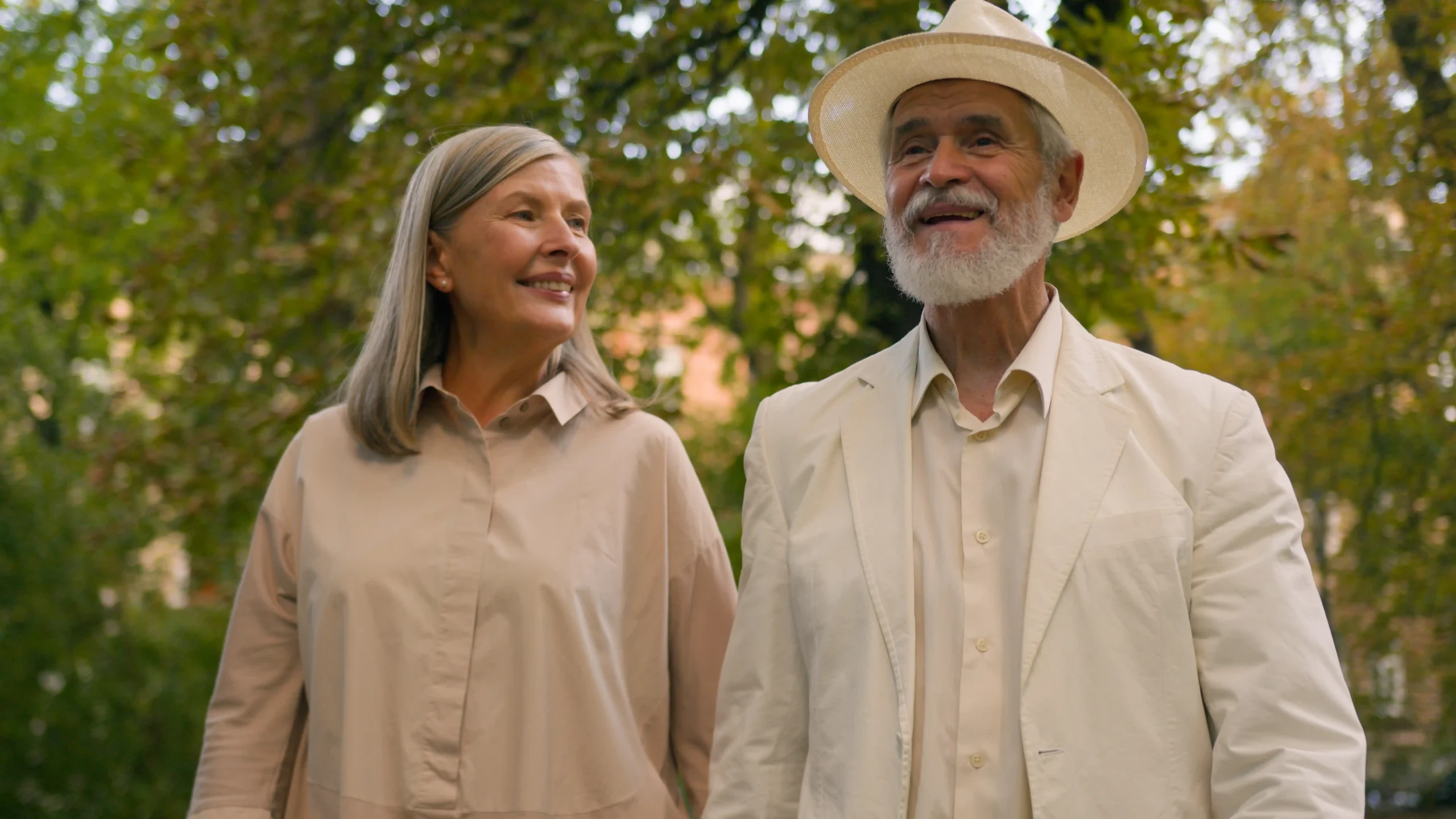 The image shows a senior couple, outdoors, walking and smiling. It illustrates the text about residence visa for foreign retirees in Brazil.