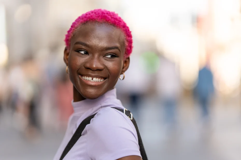The image shows a smiling young black woman with short, pink hair. It illustrates the text about Brazilian nationality.