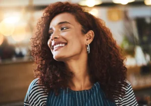La imagen muestra a una joven de cabello rizado sonriendo. Ilustra el texto sobre la nacionalidad brasileña.