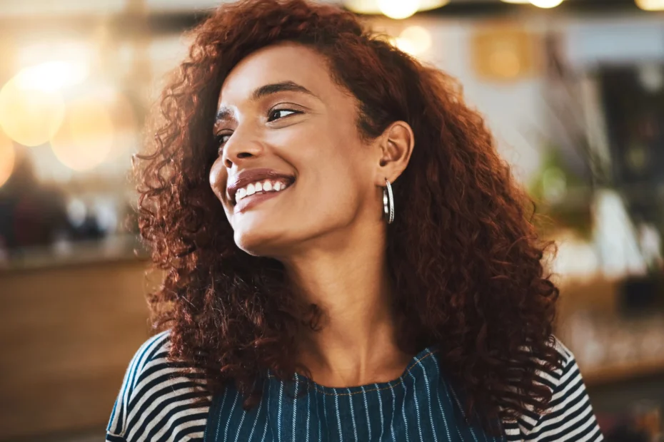 La imagen muestra a una joven de cabello rizado sonriendo. Ilustra el texto sobre la nacionalidad brasileña.