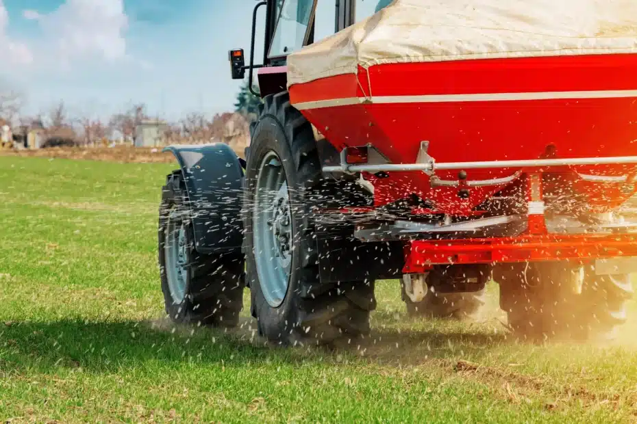 La imagen muestra un tractor agrícola fertilizando la plantación e ilustra el texto: Importación de Fertilizantes: lo que usted debe saber de Koetz Advocacia.