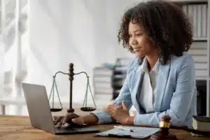 The image shows a young lawyer in her office, using her laptop. It illustrates the text about lawyers specializing in contracts.