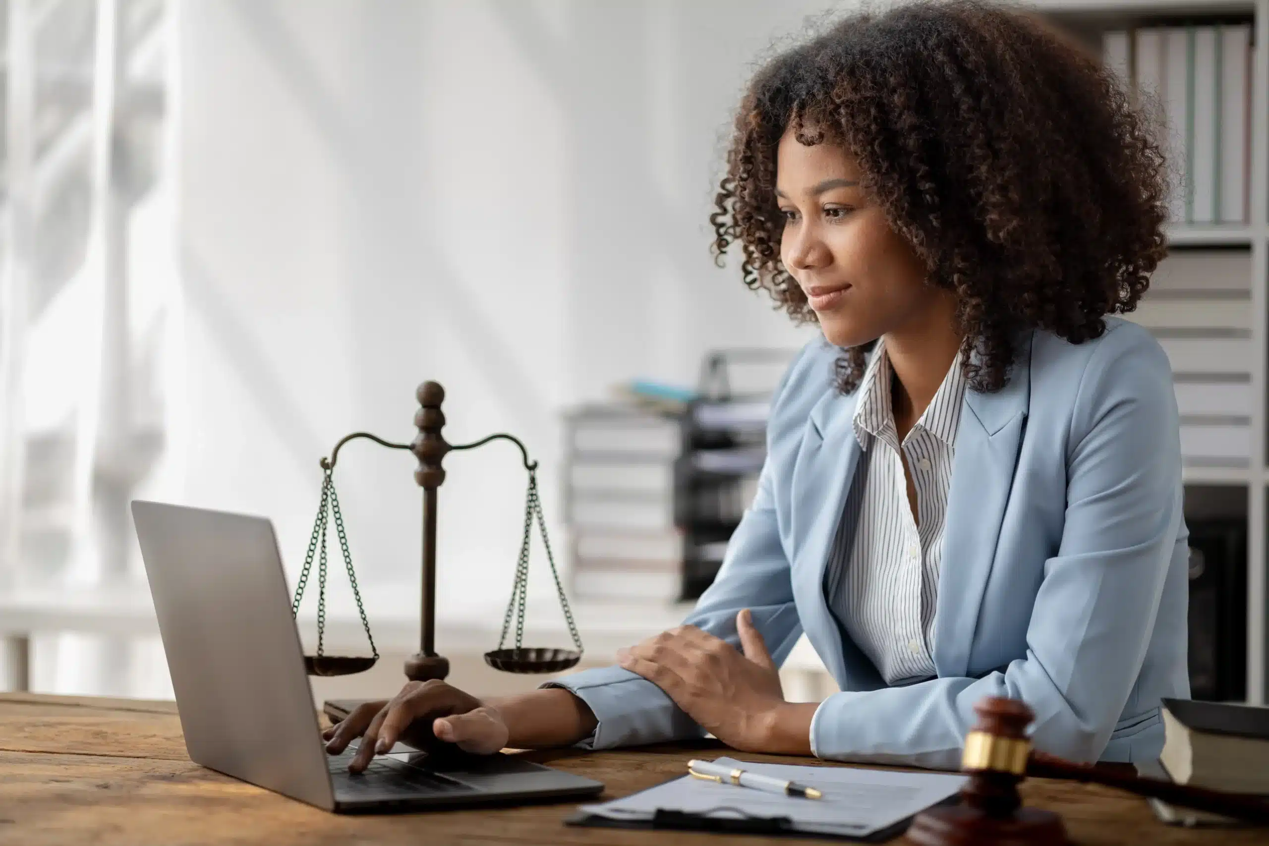 The image shows a young lawyer in her office, using her laptop. It illustrates the text about lawyers specializing in contracts.