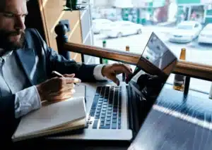 The image shows a businessman wearing a suit, working in front of a laptop. It illustrates the text about requirements for employment contract.