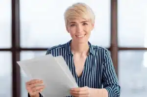 The image shows a smiling businesswoman analyzing documents in her office. It illustrates the text about articles of association or business application.