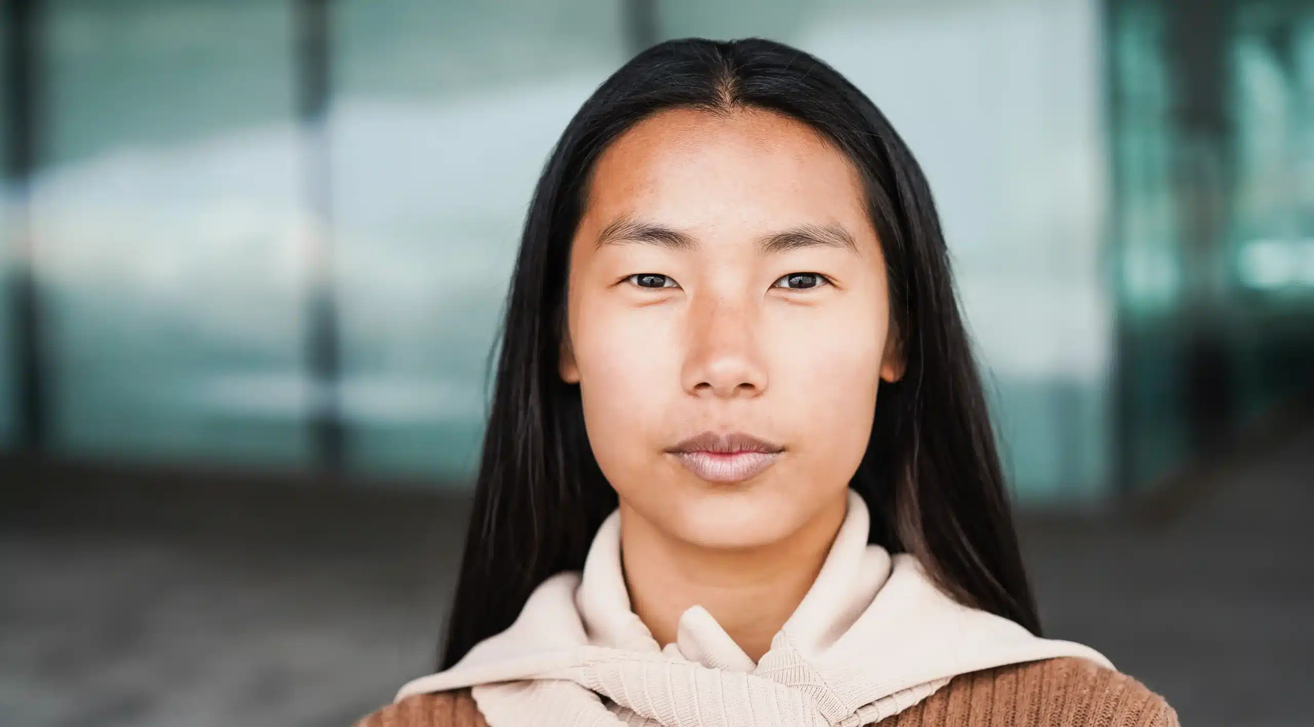 The image shows a young Asian woman with a serious expression, looking at the camera. It illustrates the text about refugee support services.