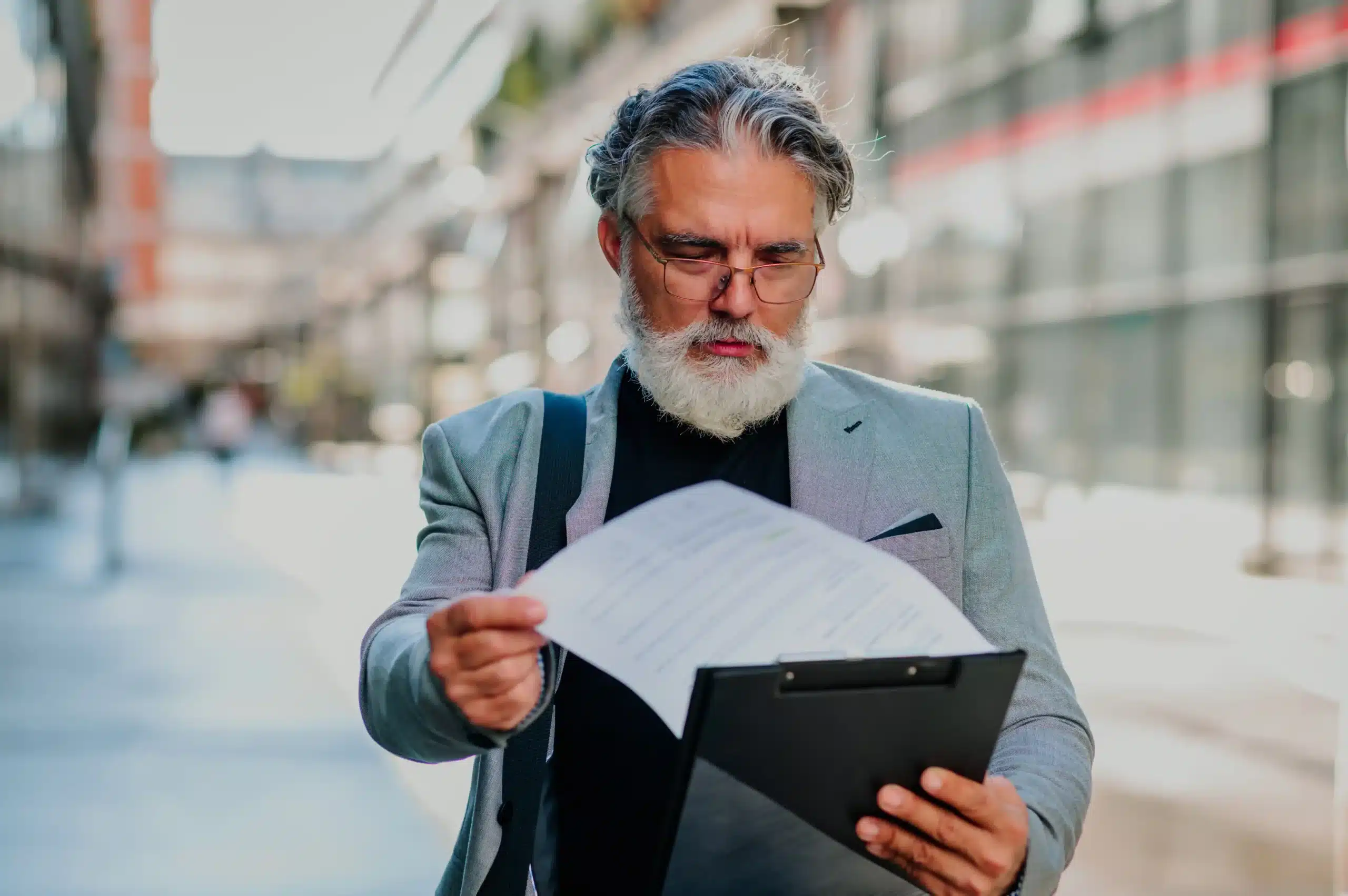 The image shows a senior businessman standing outside and reading a report on a clipboard. It illustrates the text about contract termination.