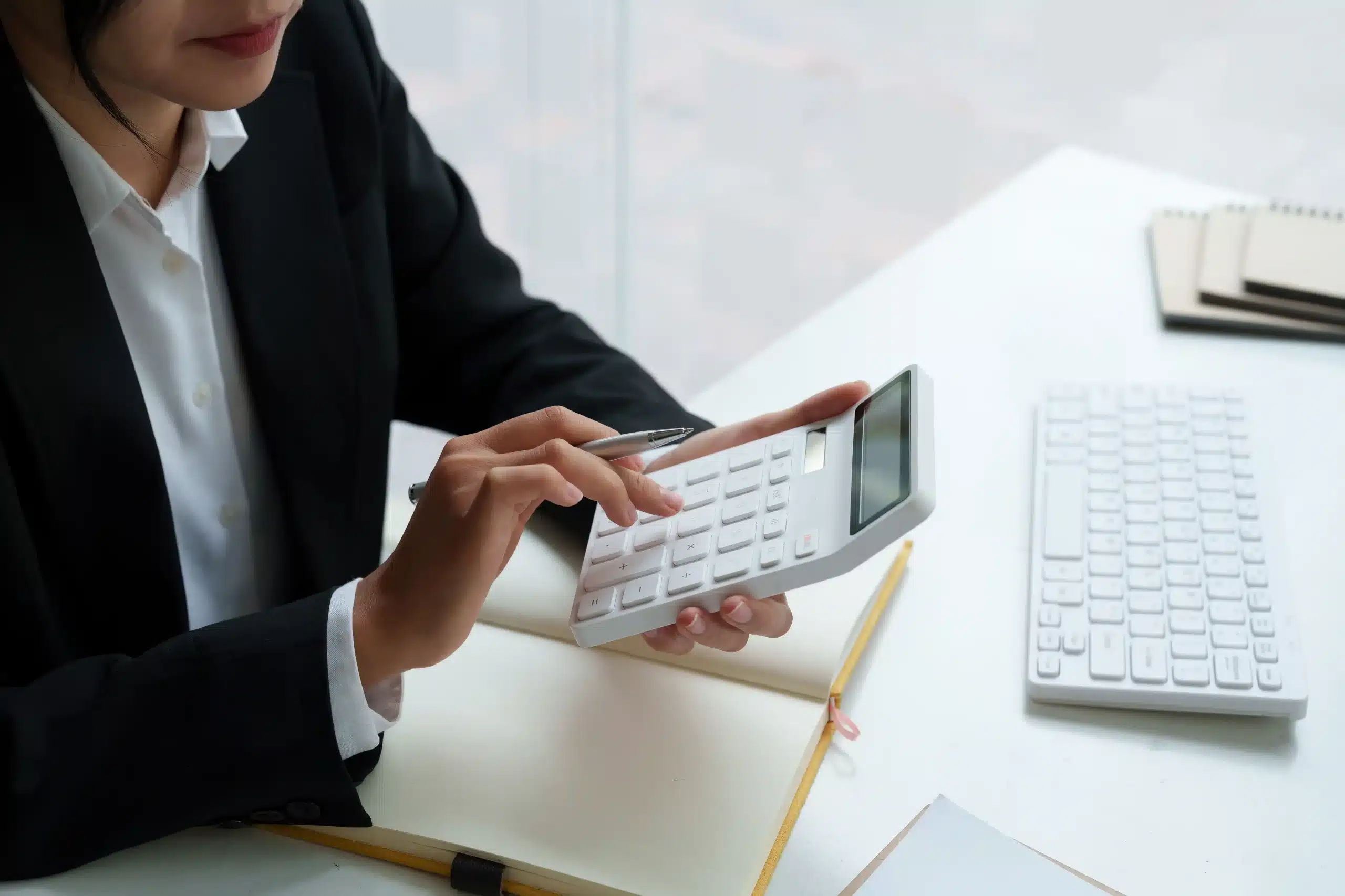 The image shows a businesswoman's hand performing calculations on a calculator held in both hands. It illustrates the text on double taxation agreement.